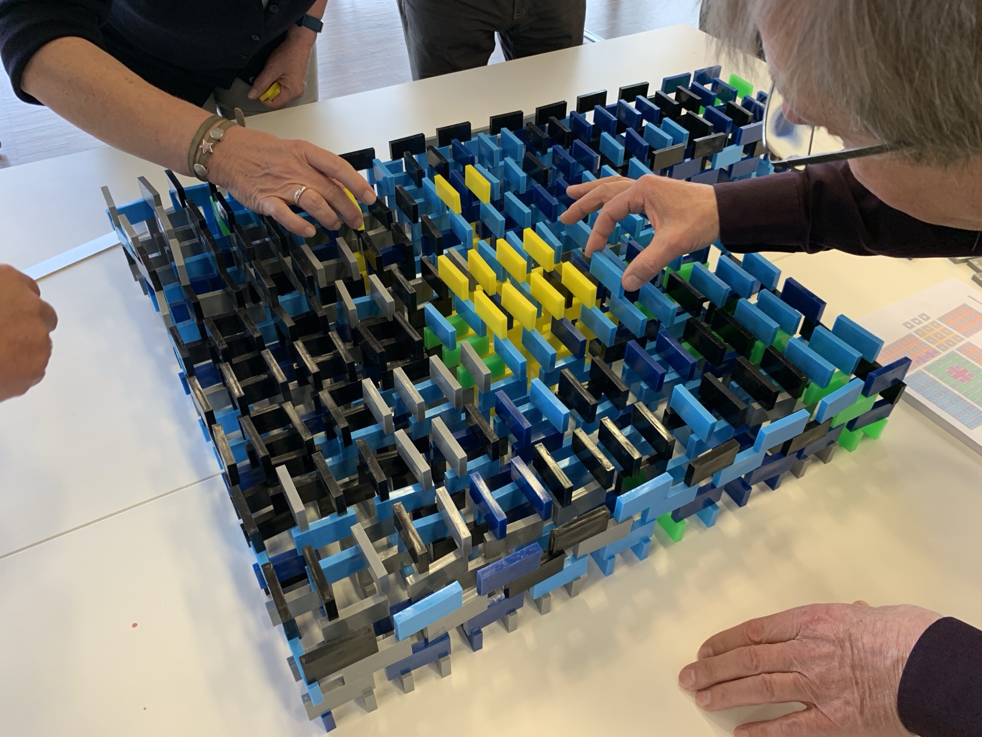 Mehrstöckige Dominokonstruktion in Blau und Grün, im Team aufgebaut